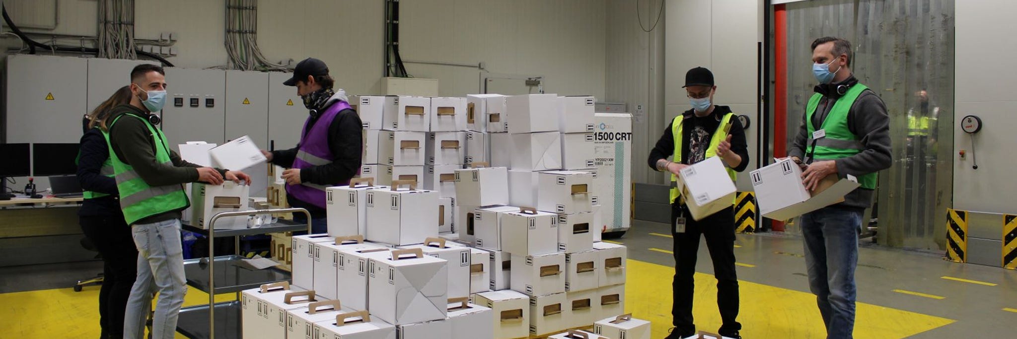 Mehrere BioNTech-Mitarbeiter mit Kartons in einer Lagerhalle