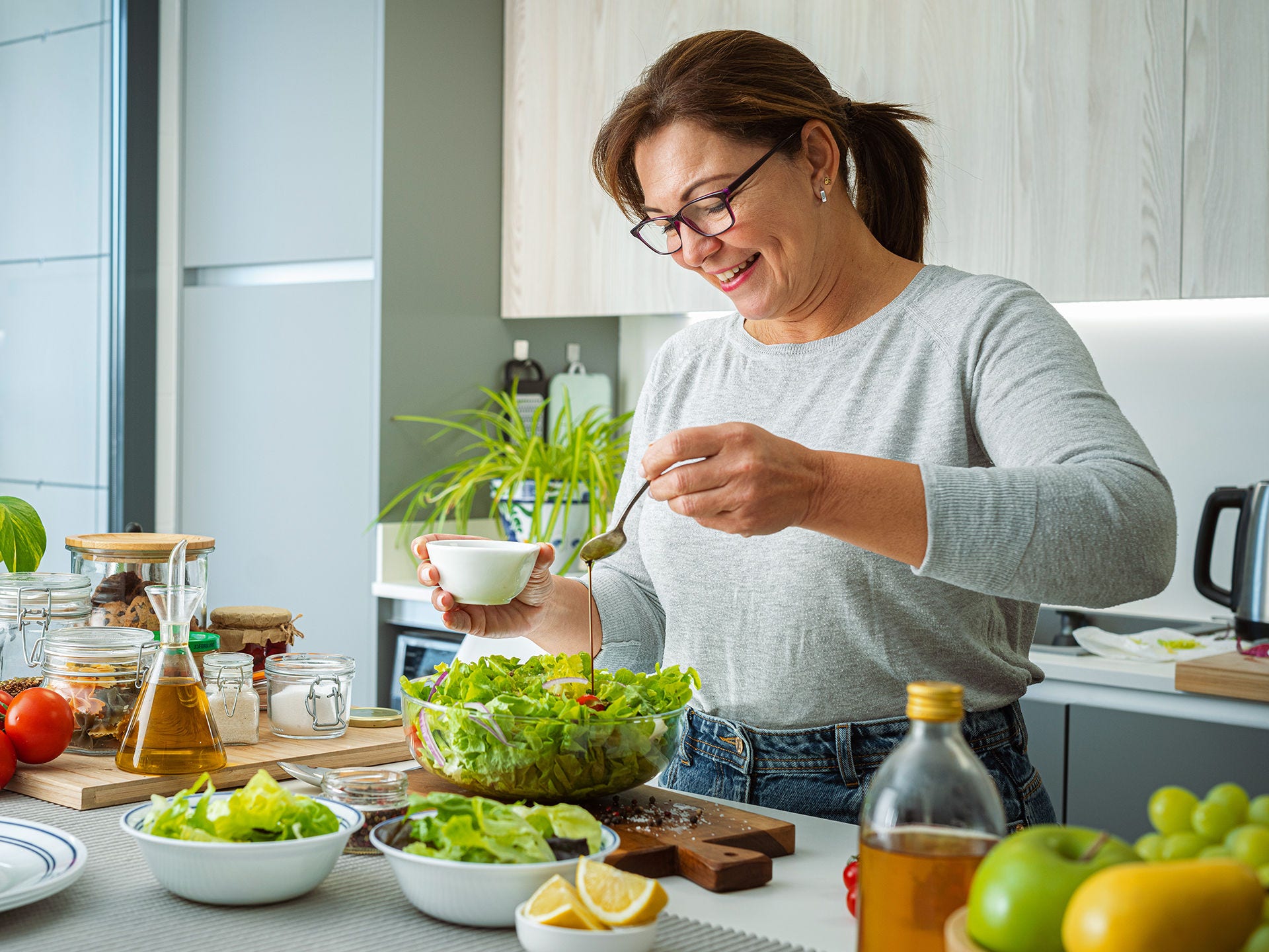 Frau mit Diabetes mellitus bereitet einen diabetikerfreundlichen Salat zu. Bei Diabetes kann der Körper Infektionen oft weniger effektiv abwehren, was das Risiko für einen schweren Corona-Krankheitsverlauf erhöhen kann.