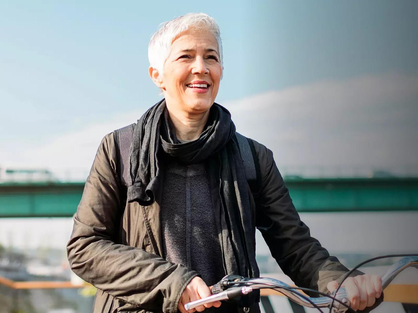 Eine ältere agile Frau fährt zufrieden Fahrrad. Es gibt Hinweise, dass Corona-Impfungen das Risiko für Long COVID senken können.
