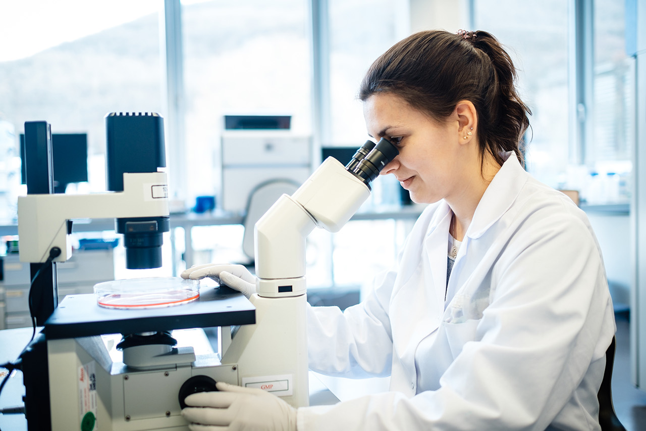 BioNTech-Laborantin schaut durch ein Mikroskop