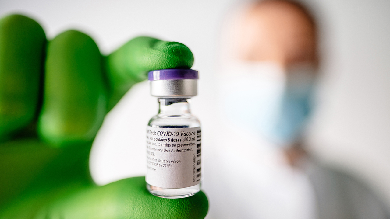 Mediziner hält COVID-19 Impfdosis in Händen